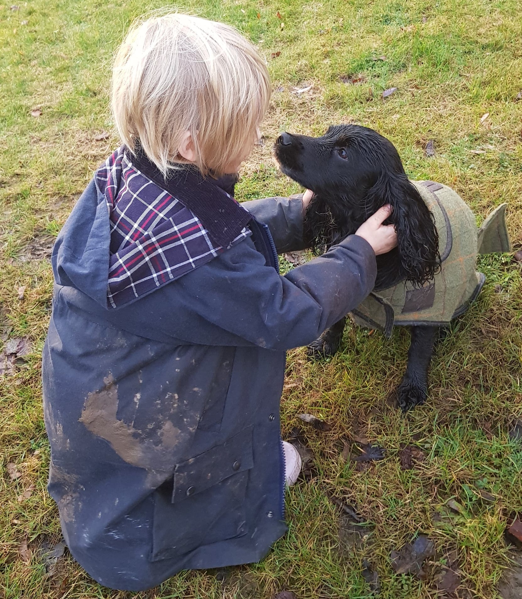 Barn i jaktkläder gosar med cockerspaniel på jakt
